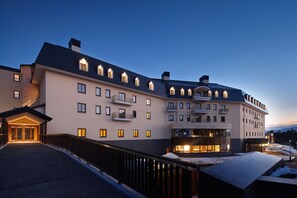 A large hotel with multiple balconies and a well-lit entrance. - Lotte Arai Resort (Myoko)