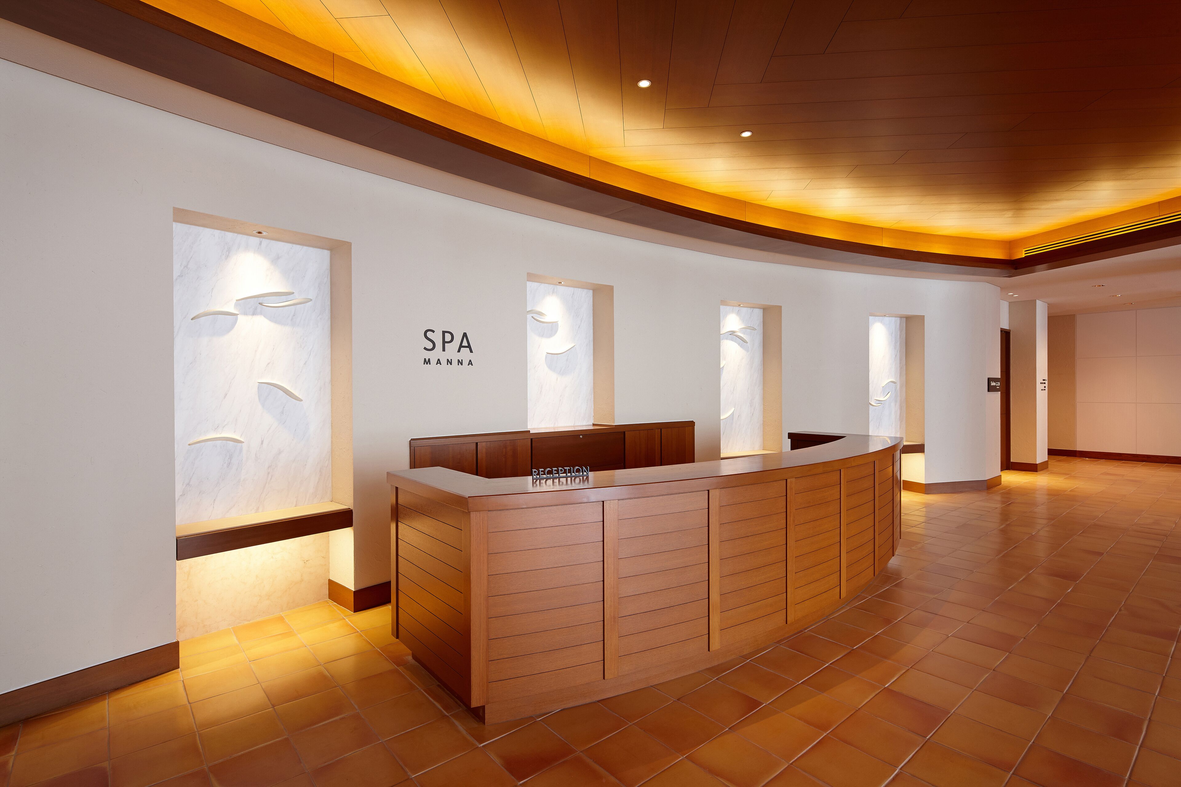 A reception area with a wooden reception desk, a sign reading "SPA Manna," and a reception counter.