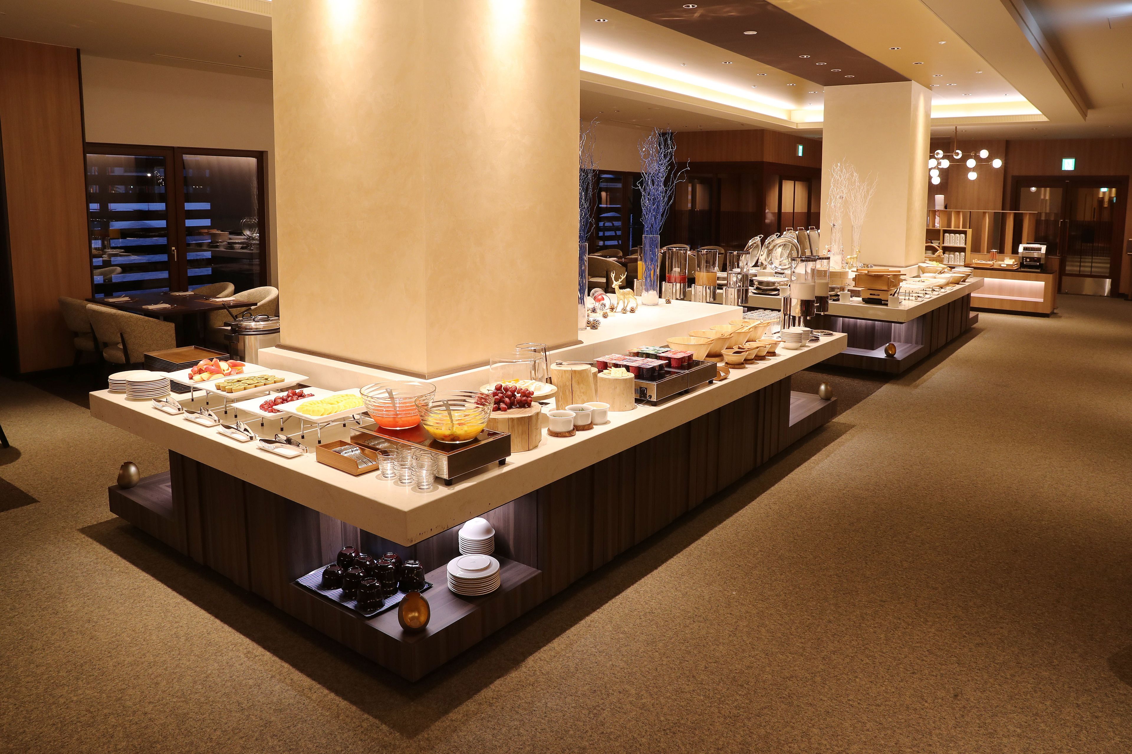 Ein reichhaltiges Buffet mit verschiedenen Speisen und Besteck, eine Sitzecke mit Stühlen und eine große Säule.