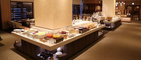 Ein reichhaltiges Buffet mit verschiedenen Speisen und Besteck, eine Sitzecke mit Stühlen und eine große Säule.