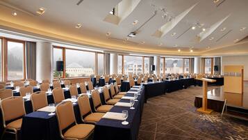 A conference room with long tables, chairs, and a carpeted floor.
