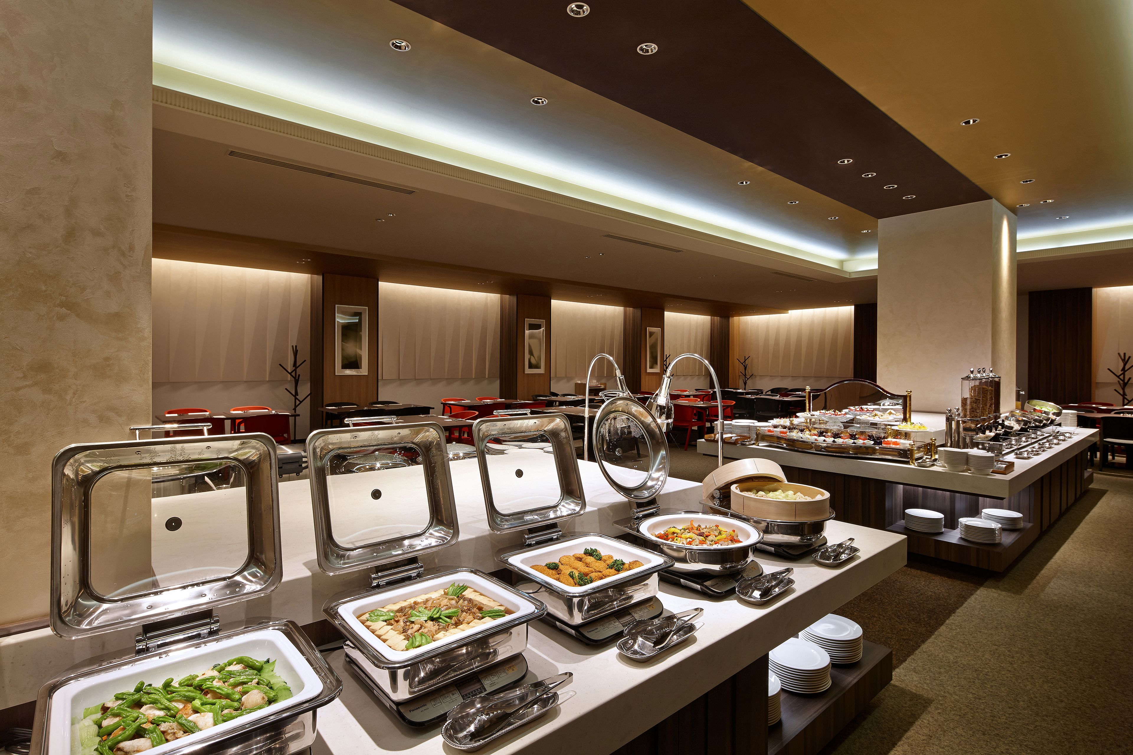A buffet setup with various food items and serving utensils.
