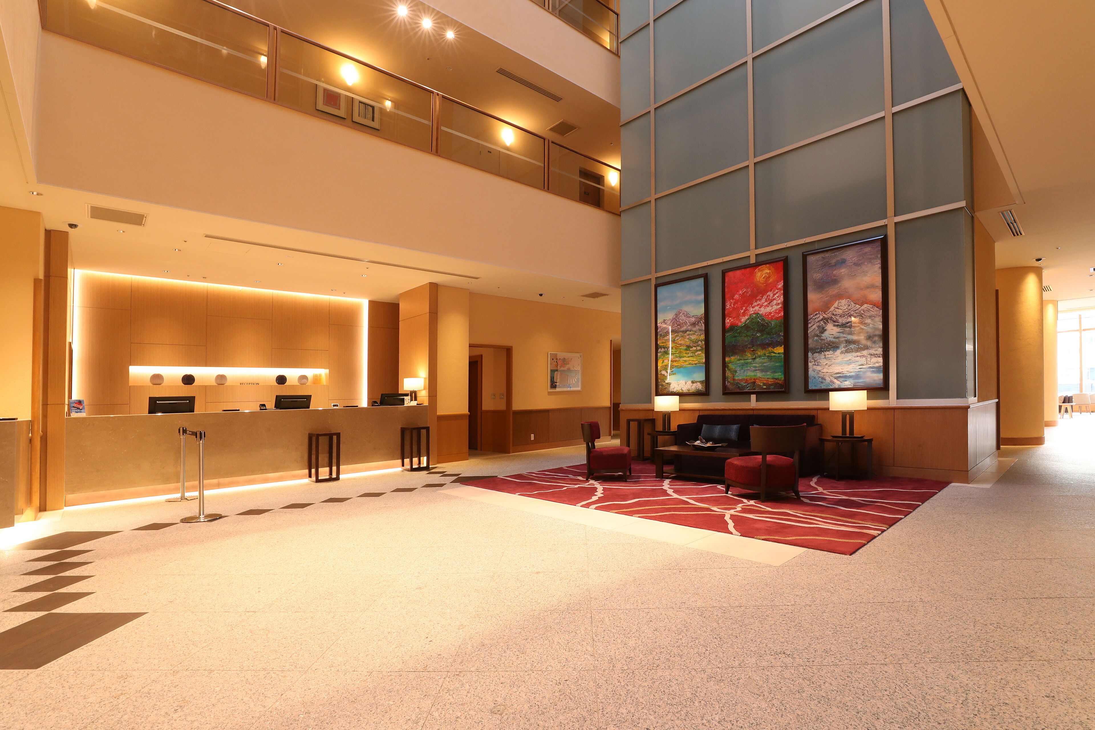 A spacious lobby with a reception desk, seating area, and artwork on the walls.