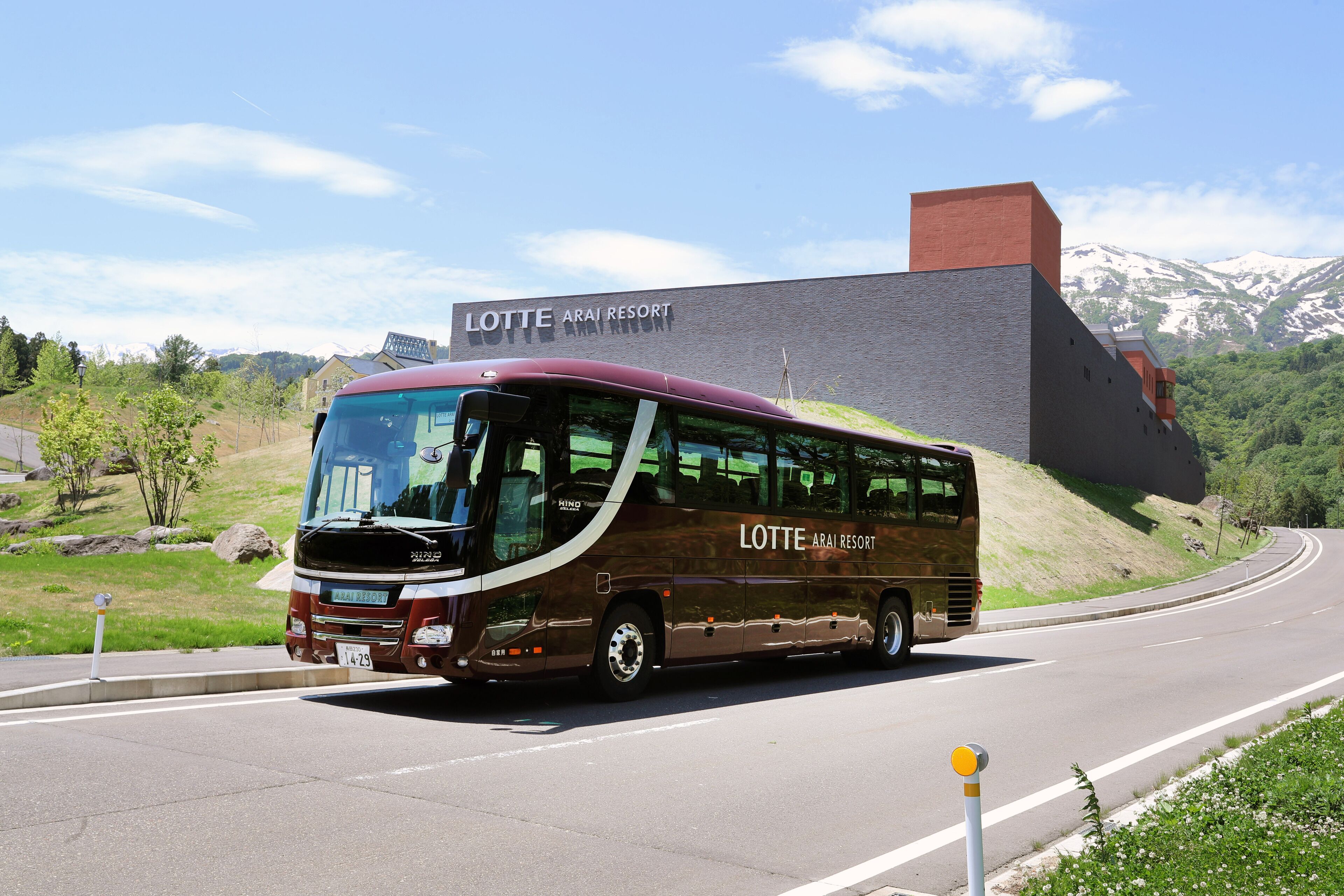 A bus with "LOTTE ARAI RESORT" written on it, parked on a road with a building in the background.