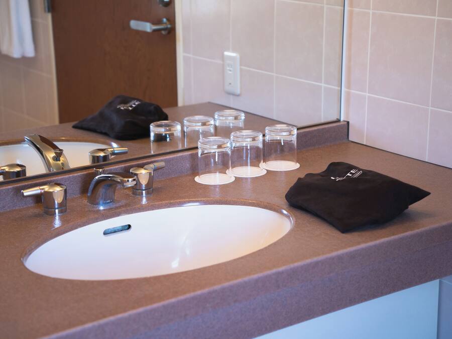 A bathroom sink with a mirror, a towel, and several clear glasses on the countertop.