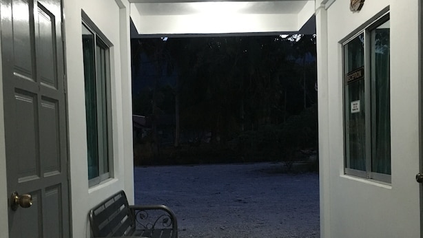 A hallway with a bench, a reception sign, and a door. - Lyaa Resthouse (Langkawi)