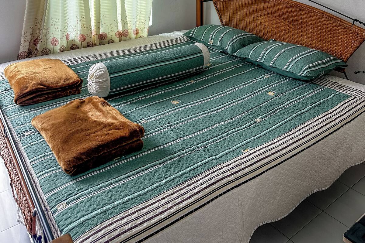 A bedroom with a bed, pillows, and a blanket.