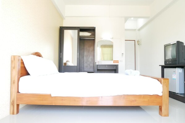 Un dormitorio con cama de madera, un armario, un espejo, un televisor y un refrigerador.