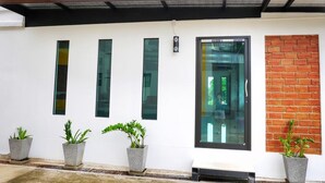 A modern building with a white facade, three vertical windows, a large glass door, and a brick accent wall. - Fang Villa Hotel (Fang)