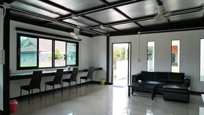 A spacious room with a black ceiling, large windows, a black sofa, and a row of chairs. - Fang Villa Hotel (Fang)