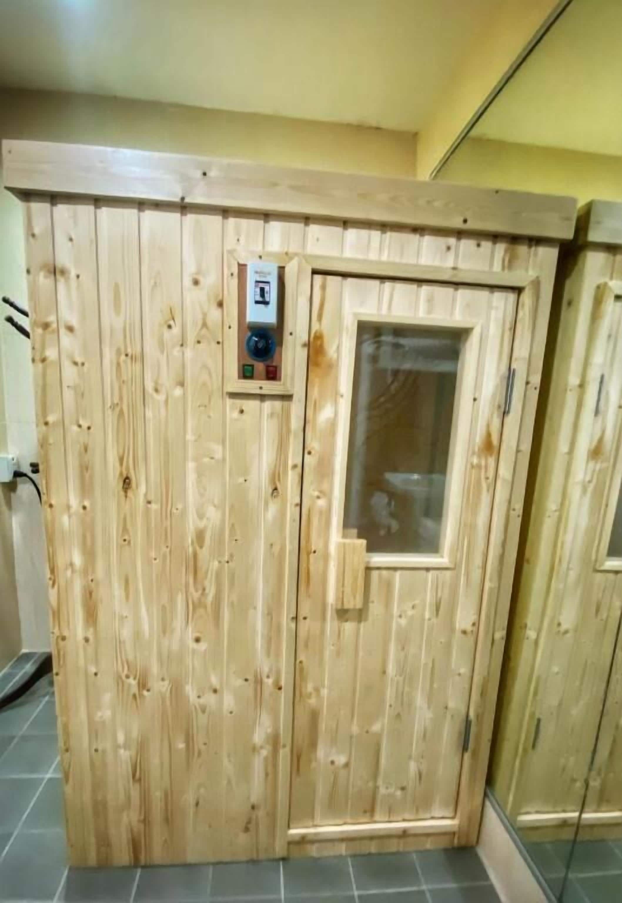 Una sauna de madera con panel de control y puerta de cristal.