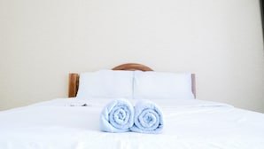 A neatly made bed with white linens and two rolled towels placed at the foot of the bed. - Fang Villa Hotel (Fang)