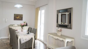A dining area with a table set for two, a console table with a vase, and a mirror on the wall. - Heraklion Old Port Apartments (Heraklion)