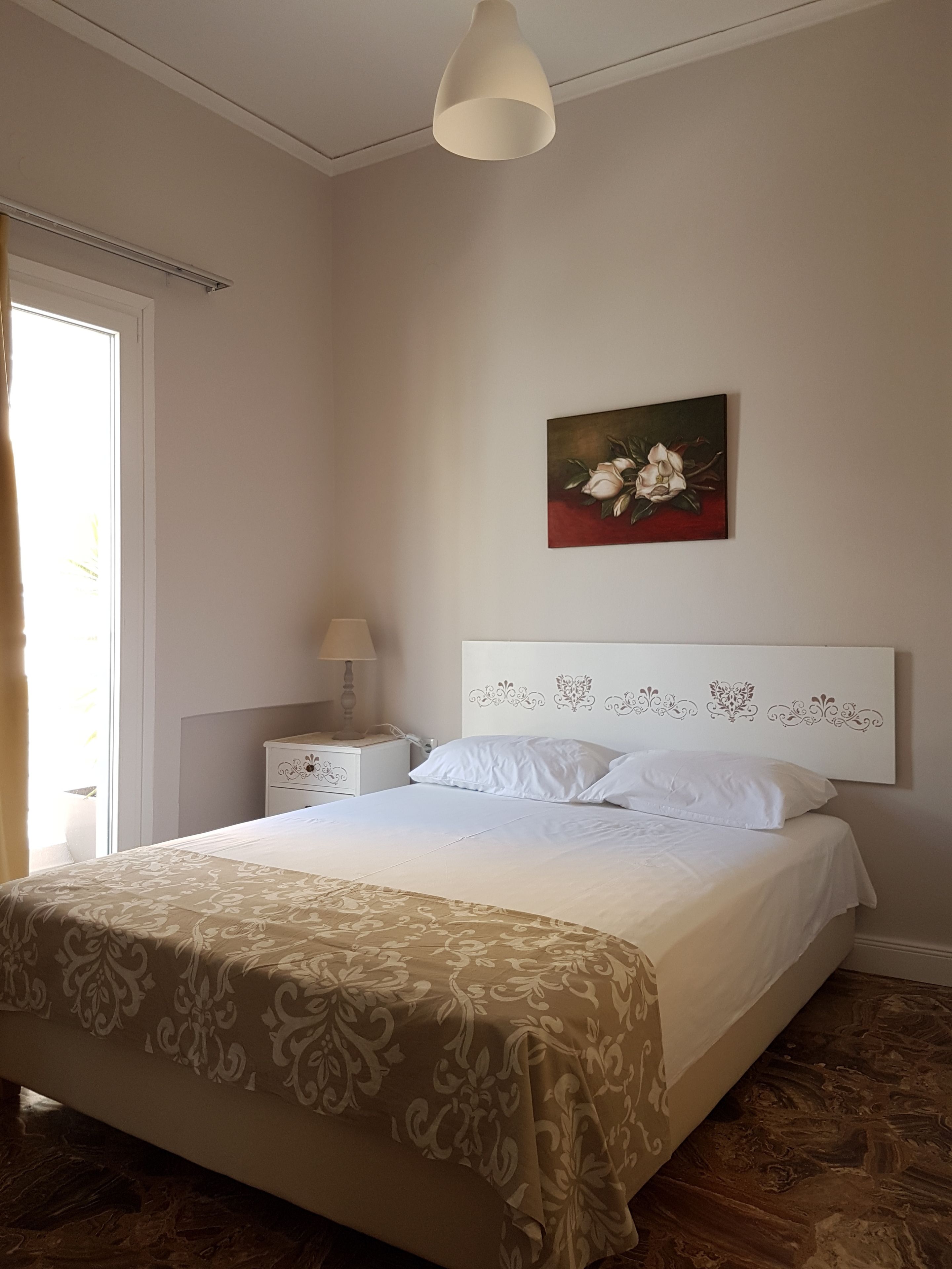 A bedroom with a bed, a nightstand, a lamp, and a painting on the wall.