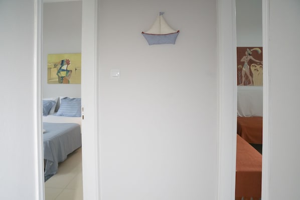 A bedroom with a bed, a nightstand, and a wall-mounted shelf with a decorative item.