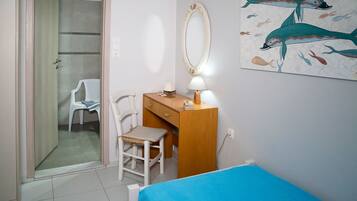 Quarto com cama, escrivaninha com cadeira, espelho e um quadro de peixe na parede.