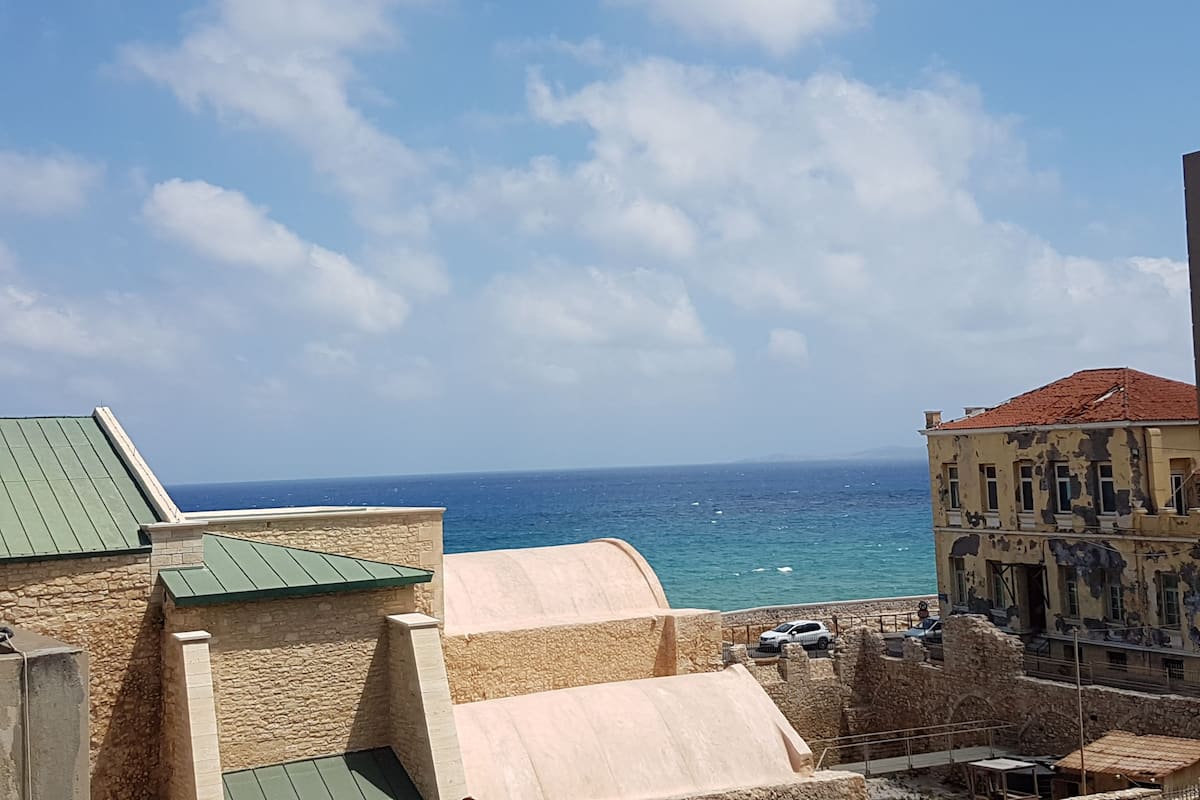A coastal view with a stone building and a sea in the background.