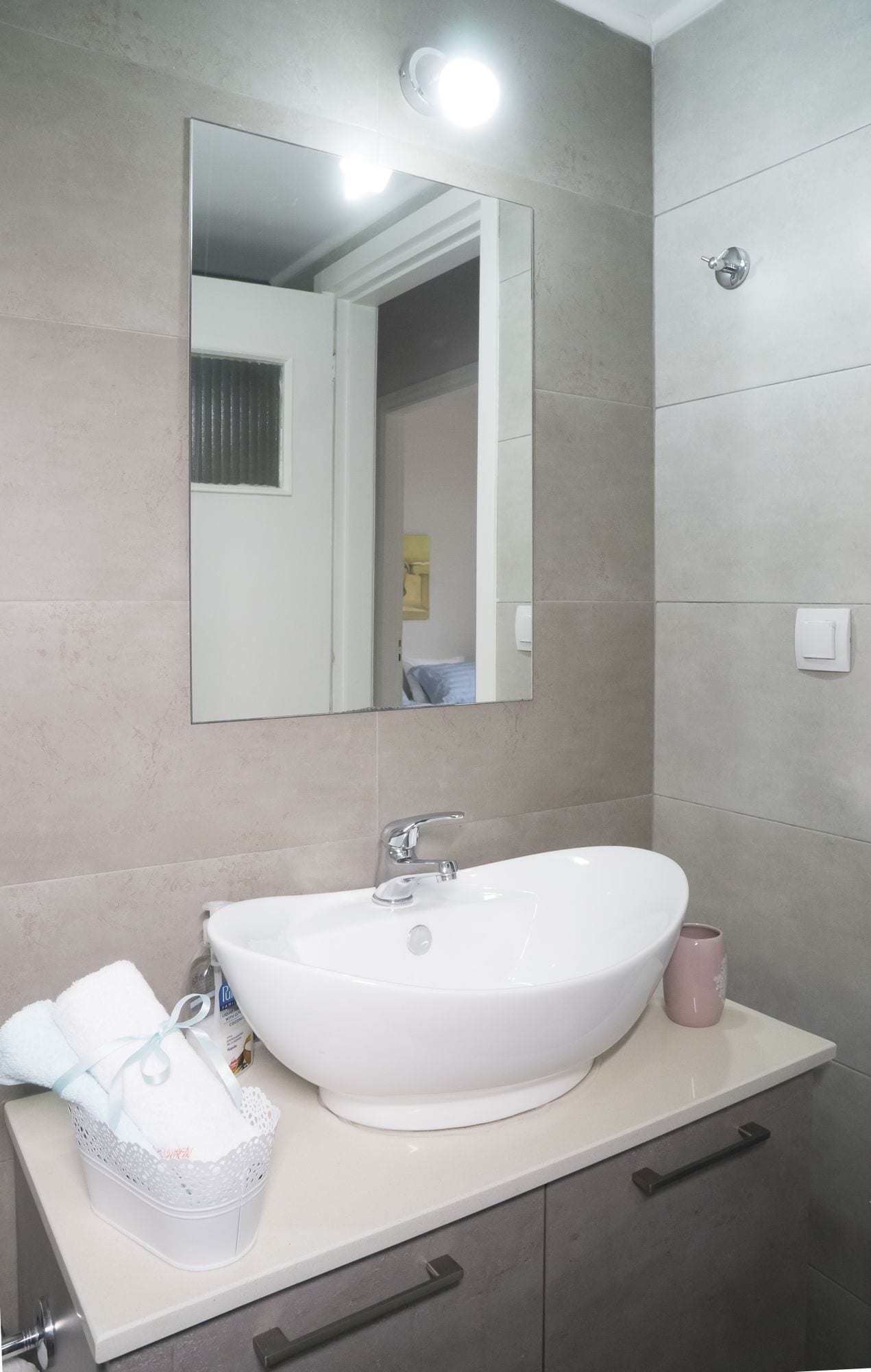 A bathroom with a white sink, a mirror, and a towel rack.