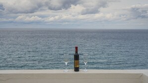 A bottle of wine and two glasses on a ledge overlooking the sea. - Heraklion Old Port Apartments (Heraklion)