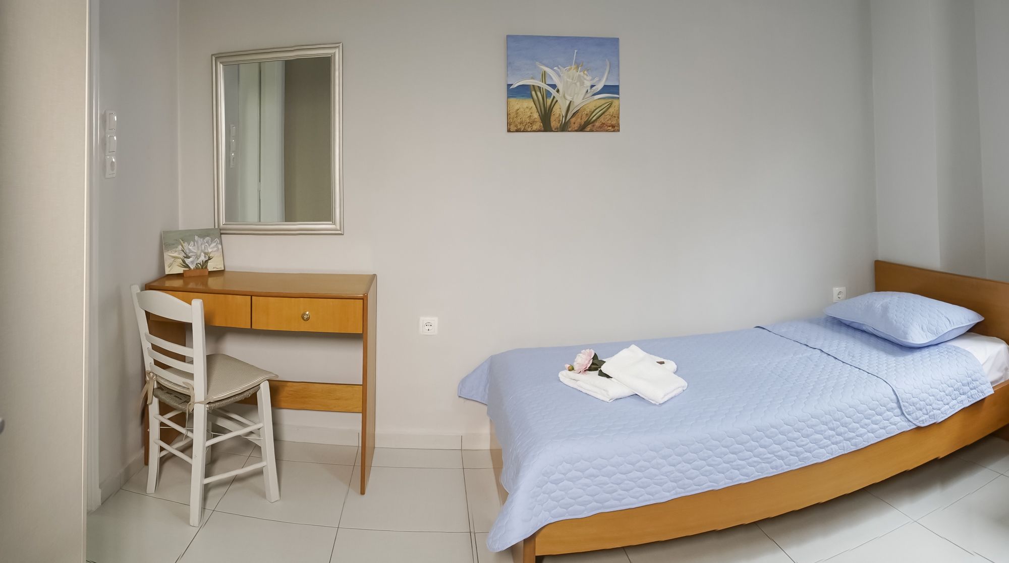 A bedroom with a bed, a desk, and a chair.