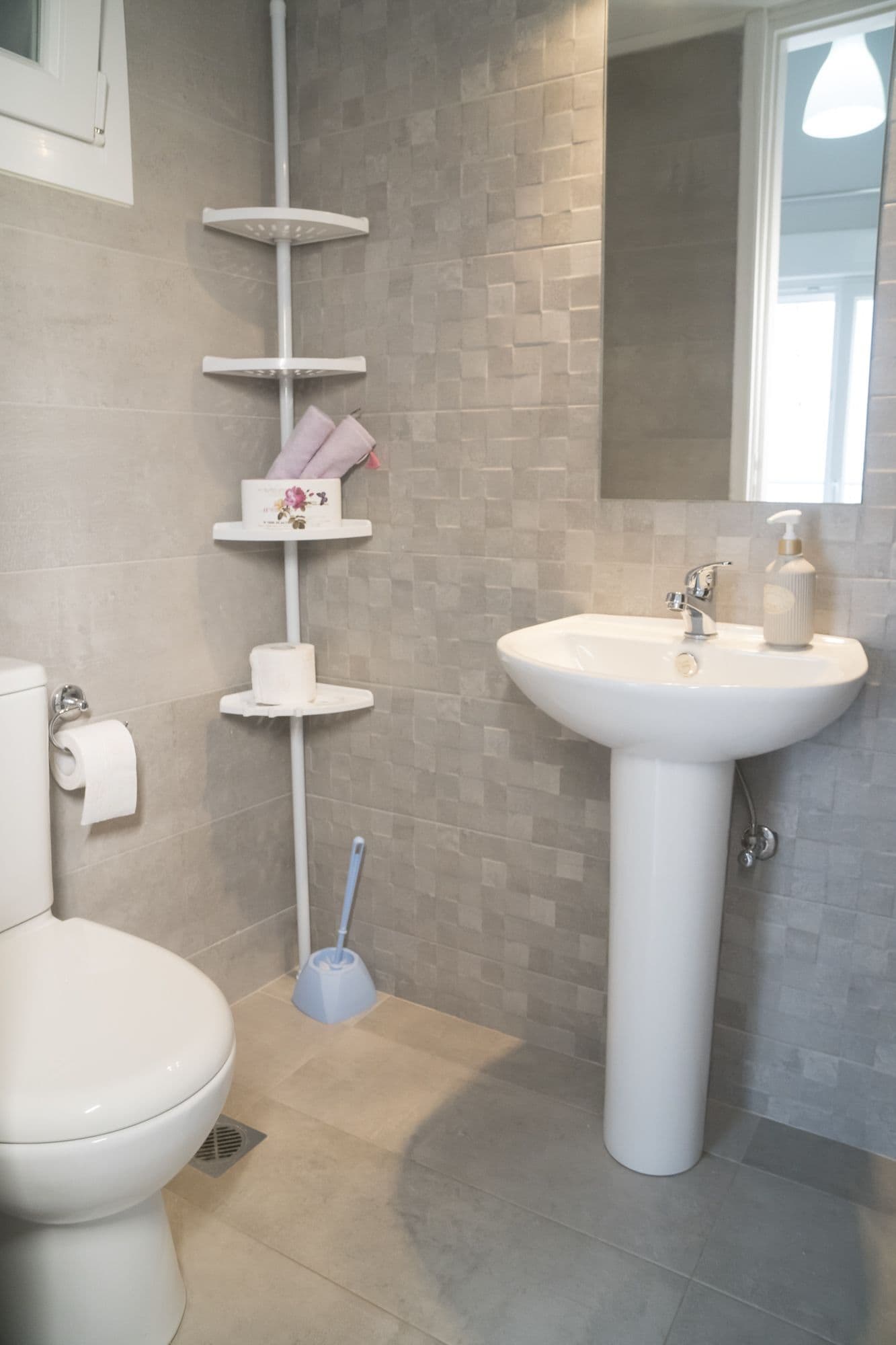 Un baño con inodoro, lavamanos y perchero para toallas.