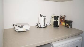 Un piano di lavoro in cucina con una macchina da caffè, un bollitore e una confezione di cialde per il caffè.