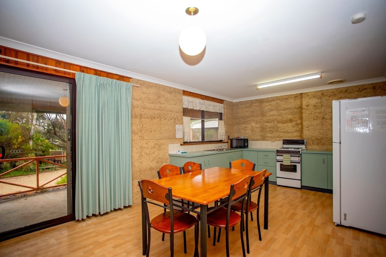 A compact kitchen with a dining table and chairs, a refrigerator, a microwave, and a stove.