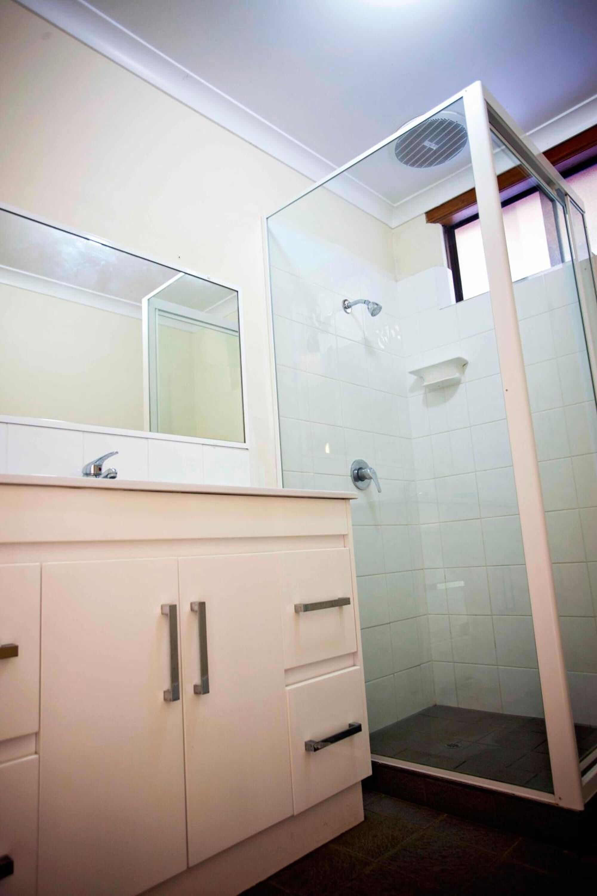 A bathroom with a white vanity, a mirror, and a glass-enclosed shower.