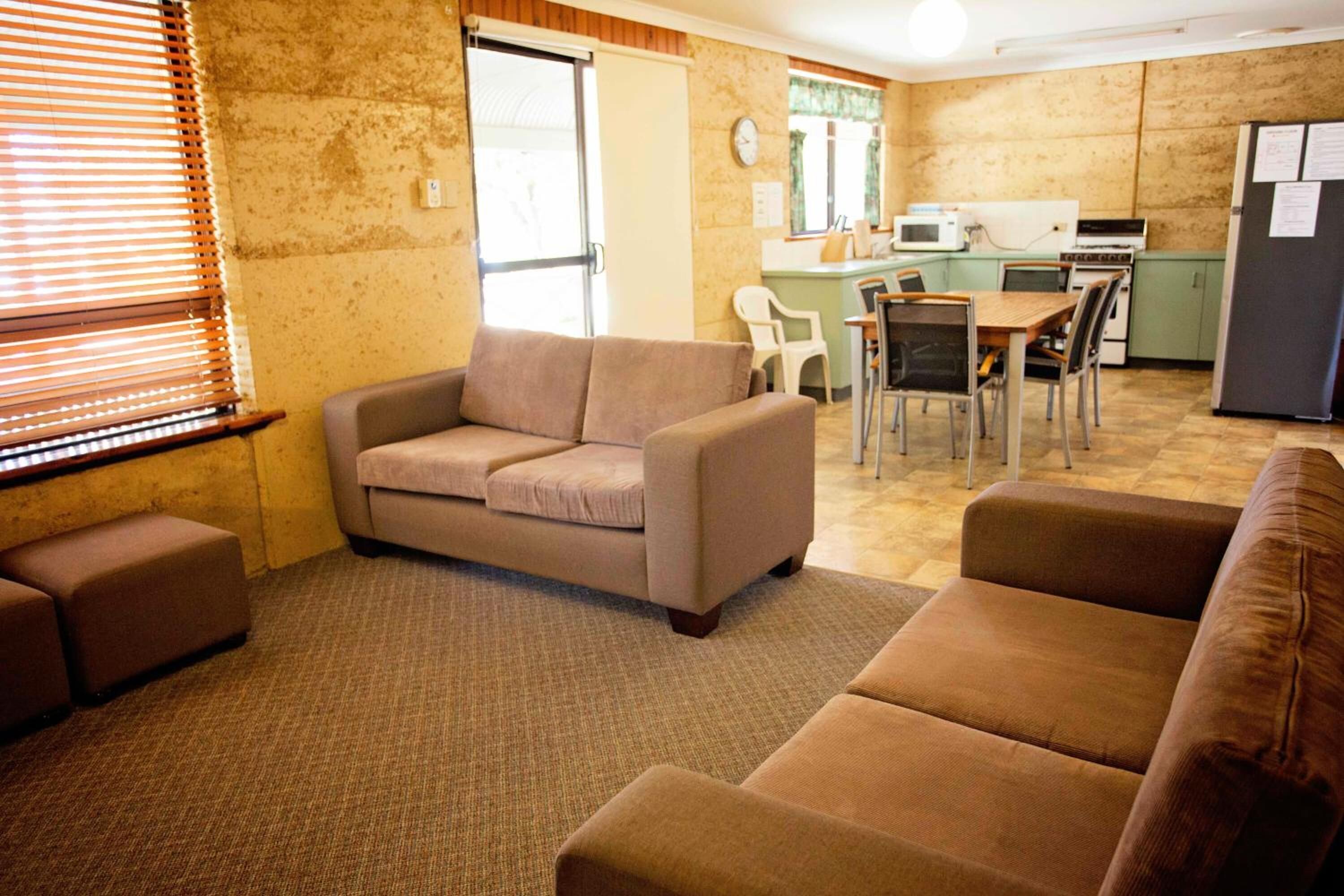 Una sala de estar con sofá, reposapiés y un comedor con sillas y una mesa.