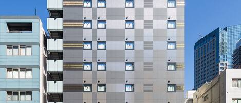 Un hotel de varios pisos con un llamativo letrero de "APA HOTEL" en la parte superior.