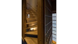 A wooden staircase with a railing, leading to a room with a view through a shoji screen.