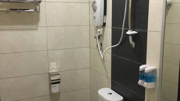 Un baño moderno con inodoro, bidé y lavamanos. Se observa un perchero con toallas dobladas, un secamanos y un dispensador de jabón.