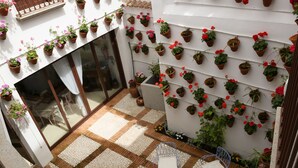 A patio with a checkered floor, a round table, and blue metal chairs. - Lantigua Casa Rural (Hinojosa del Duque)