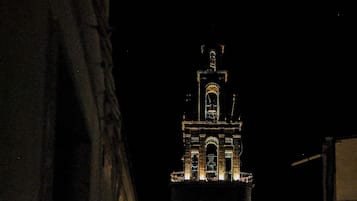 A nighttime view of a historic building with a prominent tower, featuring illuminated architectural details and a clear view of its facade.