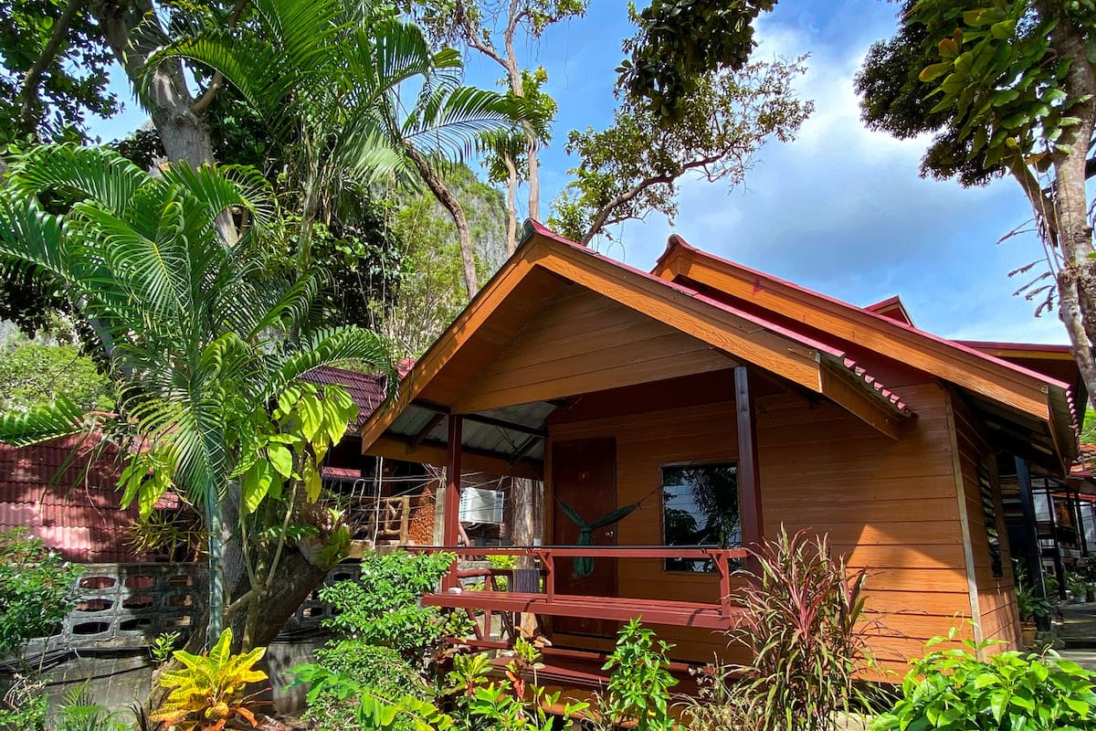 Eine Holzhütte mit Veranda, umgeben von üppiger Vegetation und Bäumen.