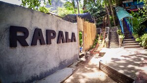 Eine Betonwand mit dem Schriftzug "RAPALA" in großen Buchstaben, ein Holzzaun, eine Treppe und etwas Grün.