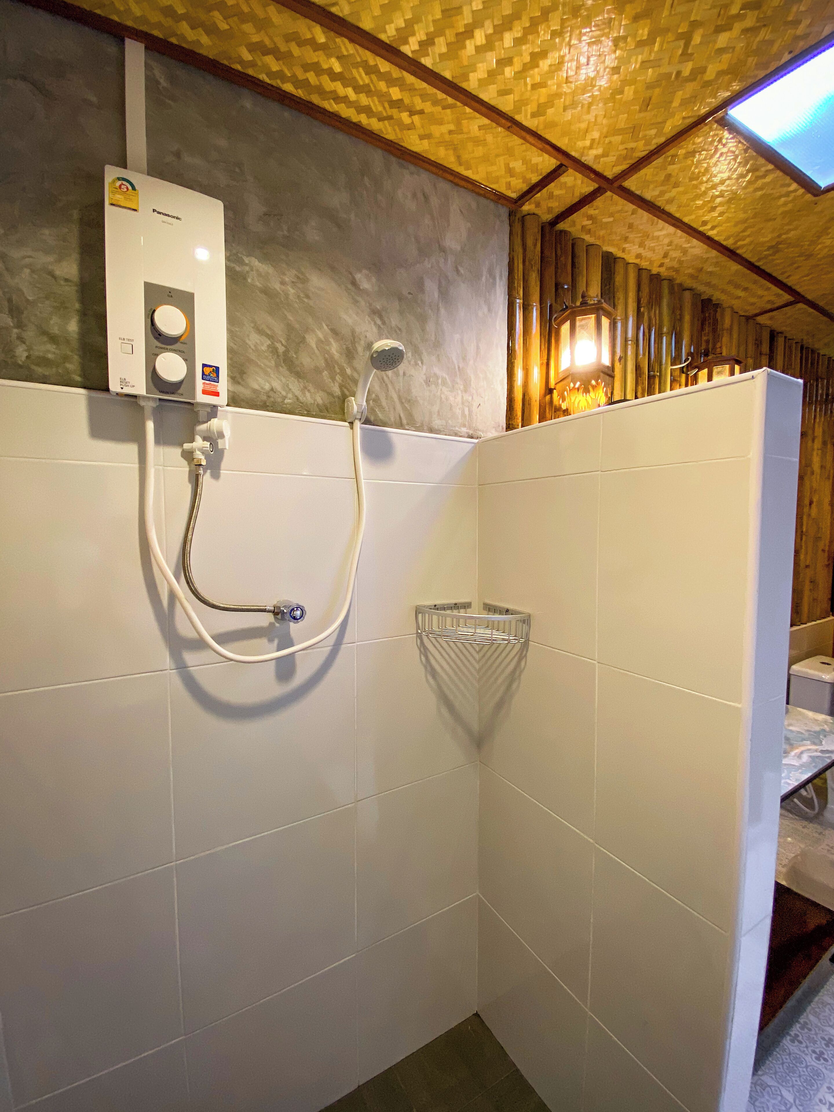 A bathroom with a shower, a towel rack, and a wall-mounted heater.