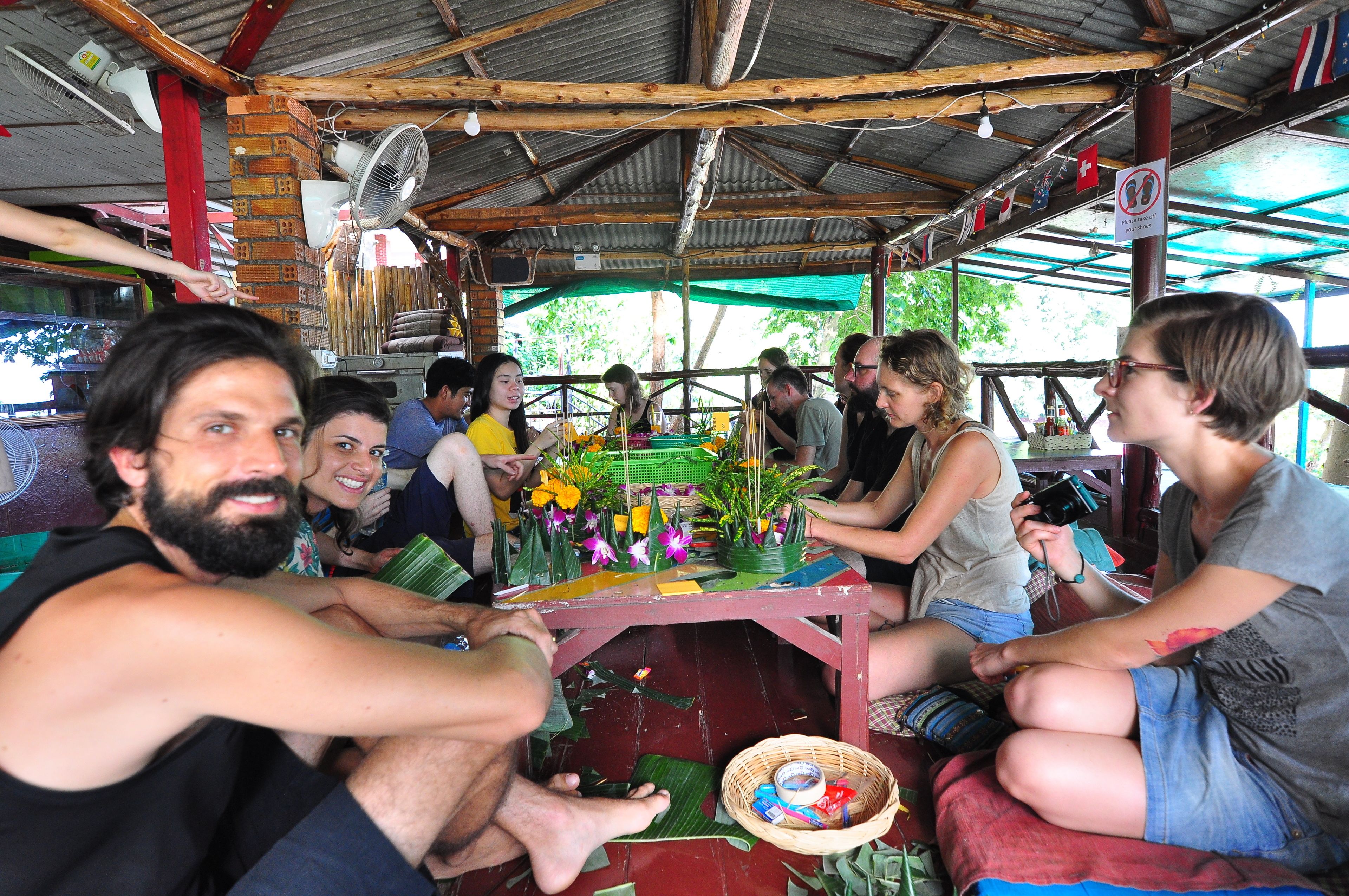 Un groupe de personnes s’est réuni autour d’une table ornée de fleurs et d’un éventail, dans un espace extérieur abrité.