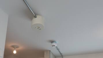 A ceiling with a light fixture and a smoke detector.