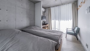 A modern hotel room with two beds, a desk with a chair, and a large window with curtains. - bmj Shinjuku Okubo (Tokyo)