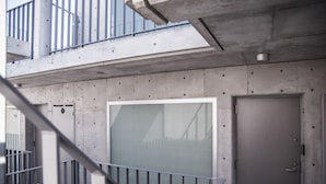 A concrete building with a large window and a door, a metal railing, and a balcony. - bmj Shinjuku Okubo (Tokyo)