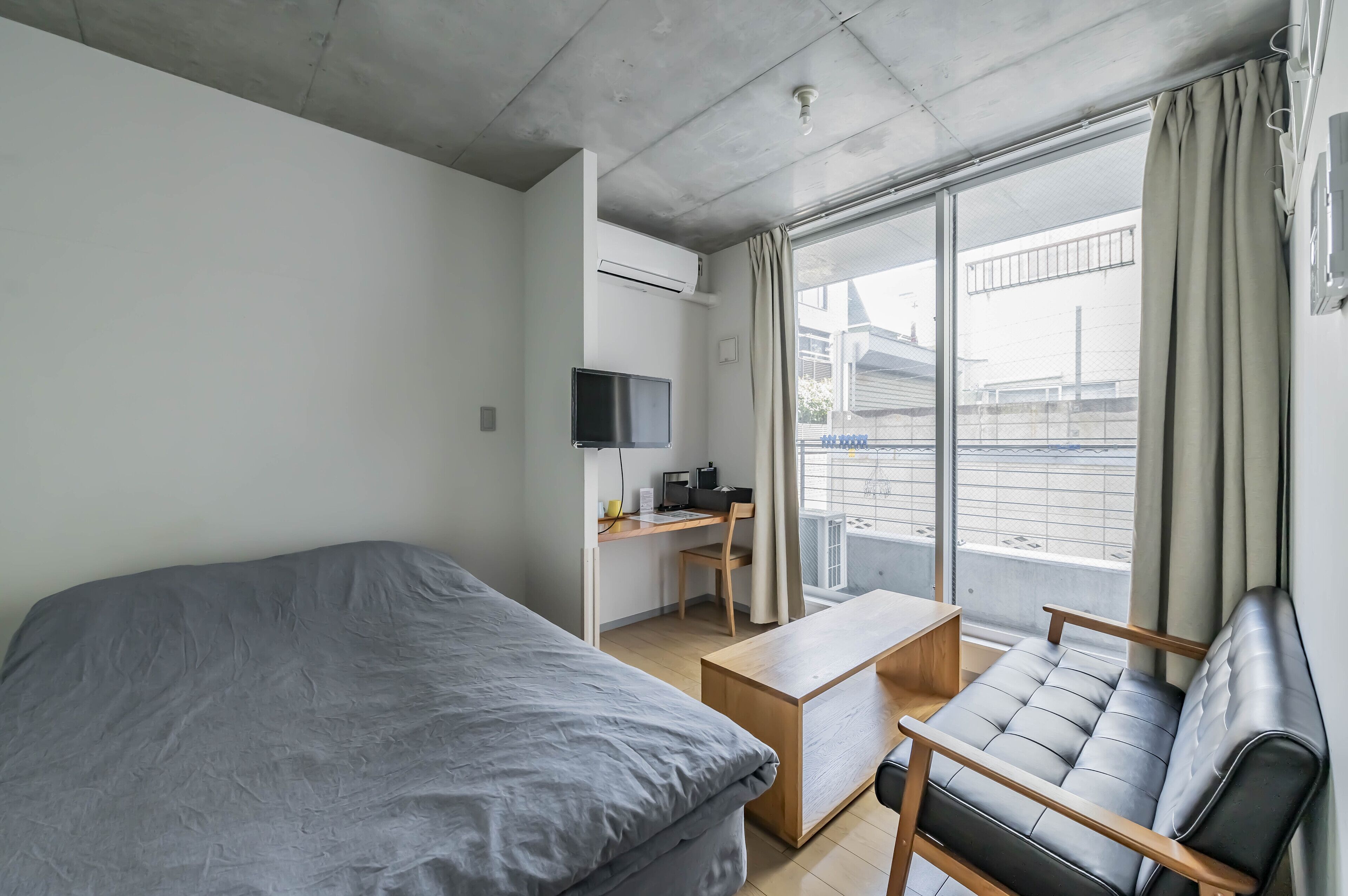 A modern hotel room with a bed, a desk, a chair, and a TV.