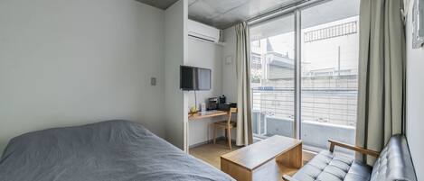 A modern hotel room with a bed, a desk, a chair, and a TV.