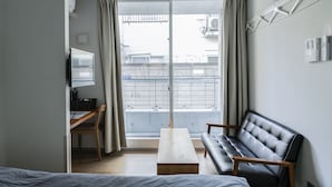 A modern room with a sofa, a wooden table, a TV, and a balcony with a view. - bmj Shinjuku Okubo (Tokyo)