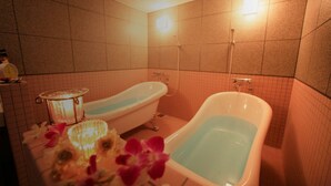 Une salle de bain avec deux baignoires, une douche et une horloge au mur.