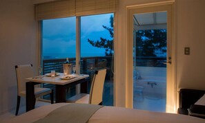 A bedroom with a bed, a dining table with chairs, a balcony with a view of trees, and a door leading to an outdoor area. - Takamiya Yunohama Terrace Seiyou Saryo (Tsuruoka)