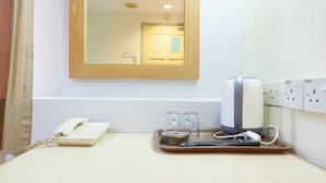 A hotel room with a wooden door, a mirror, a telephone, two glasses, a remote control, and a power outlet. - Tang City Hotel, Petaling Street, Merdeka PNB 118 Tower (Kuala Lumpur)