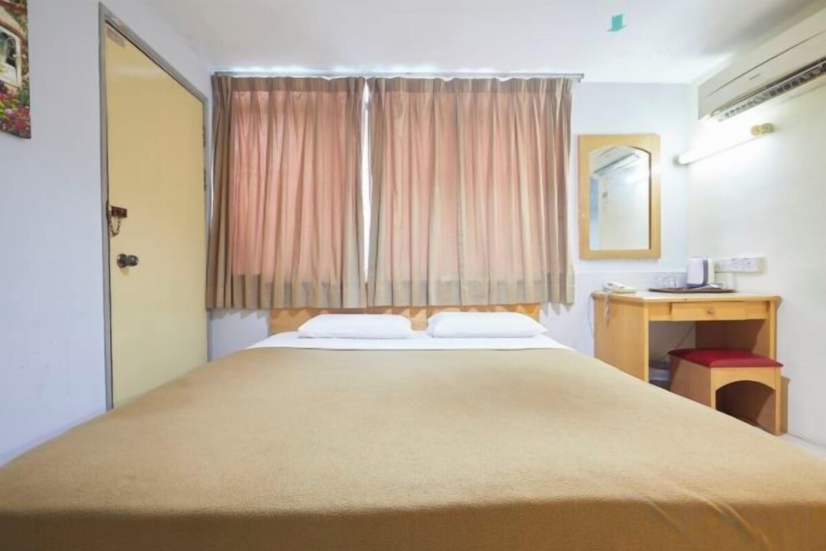 A hotel room with a bed, a desk, and a mirror.