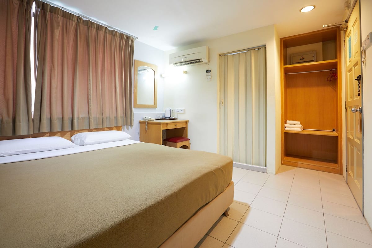Une chambre d’hôtel comprenant un lit, un bureau, un appareil de climatisation, une armoire et une salle de bain.