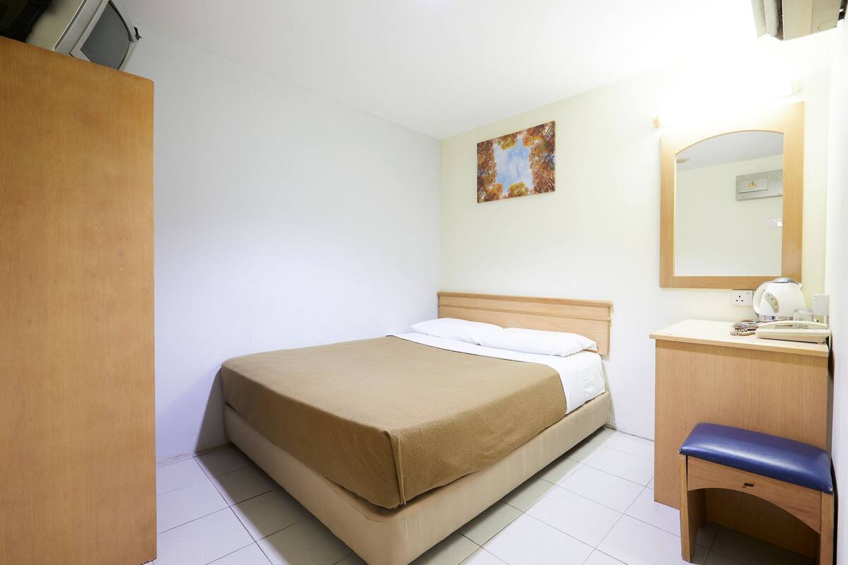 Une chambre d’hôtel avec un lit, un bureau, une chaise, un miroir et un tableau au mur.